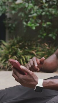 Vertical video: Holding man tapping pink phone on patio, shifting grip, final tap checking texts