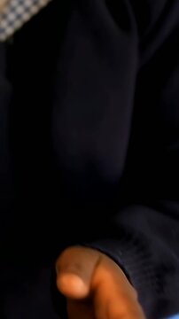 Vertical video: Tapping phone, pupil reacting and laughing at desk, in navy sweater, checked collar