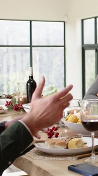 Vertical video: Talking left diner in green top gesturing grabbing fork reaching glass at home meal