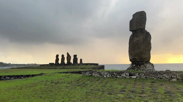  Ahu Tahai ceremonial complex on Easter Island, Chile. Historic Moai statues overlooking the Pacific Ocean on the sunset with scattered clouds.