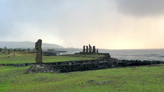  Ahu Tahai ceremonial complex on Easter Island, Chile. Historic Moai statues overlooking the Pacific Ocean on the sunset with scattered clouds.