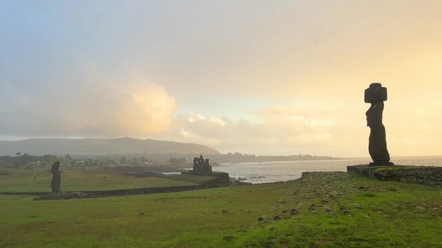  Ahu Tahai ceremonial complex on Easter Island, Chile. Historic Moai statues overlooking the Pacific Ocean on the sunset with scattered clouds.