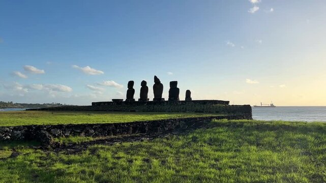  Ahu Tahai ceremonial complex on Easter Island, Chile. Historic Moai statues overlooking the Pacific Ocean on the sunset with scattered clouds.