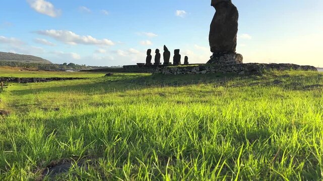  Ahu Tahai ceremonial complex on Easter Island, Chile. Historic Moai statues overlooking the Pacific Ocean on the sunset with scattered clouds.