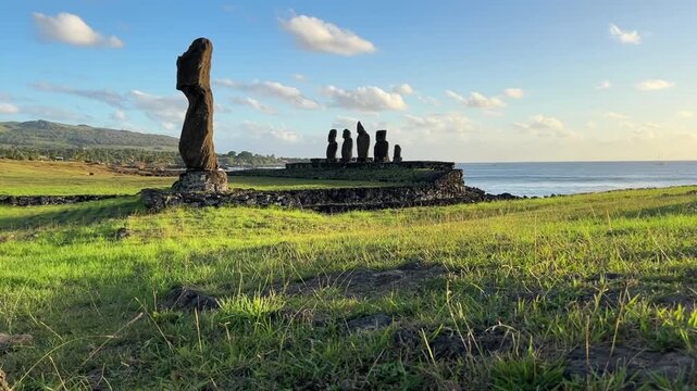  Ahu Tahai ceremonial complex on Easter Island, Chile. Historic Moai statues overlooking the Pacific Ocean on the sunset with scattered clouds.