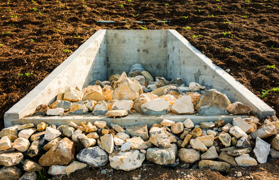Concrete drainage system with stones in a landscaped area for effective water management