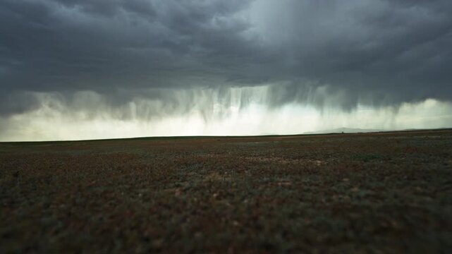 This continuous video clip captures a vast, flat landscape under a dramatic, heavy storm sky.