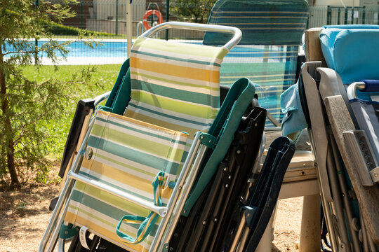 Stacked folding beach chairs beside a swimming pool