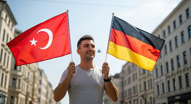 Bridging Nations: A proud man stands in a city street, holding the flags of Turkey and Germany aloft, symbolizing unity and cultural exchange.