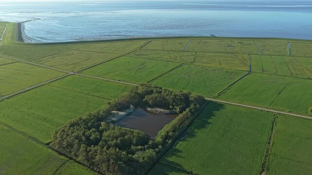 Aerial view flying over dutch polder landscape with dike and wadden sea