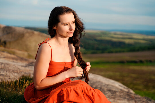 Woman sitting on a rock with a braid while looking at the landscape during the day