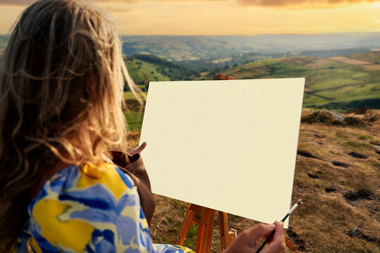 Artist paints landscape on a hill during sunset overlooking valleys and fields
