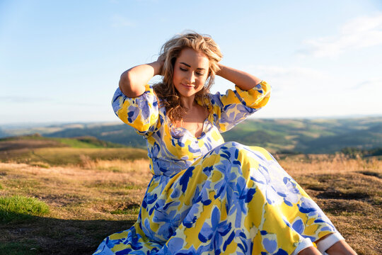 Woman sitting on a rocky outcrop in a colorful dress on a sunny day at a scenic location