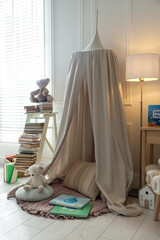 Beautiful wigwam, different toys and books in child's room. Interior design © New Africa