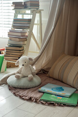 Beautiful wigwam, toy sheep and books in child's room. Interior design © New Africa
