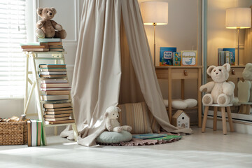 Beautiful wigwam, different toys and books in child's room. Interior design © New Africa