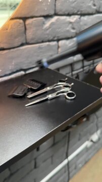 Hair dryer blowing dust from barber tools on a workstation, professional equipment cleaning, hygiene routine, barbershop maintenance, workplace safety.