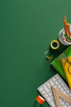 Back to school vertical flat lay with green background, stationery, keyboard, glasses and notebook for study
