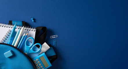 Back to school flat lay with blue school supply, notebook, calculator and stationery in backpack on banner dark blue background © ActionGP