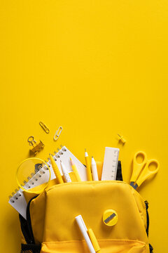 Bright yellow school supplies in backpack for back to school photo concept on bright vivid vertical background