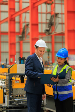 Factory Manager and Engineer Reviewing and Discussing Manufacturing Project Details in Factory.