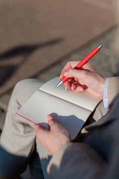 businesswoman writes notes during a meeting outside on a sunny day in the city