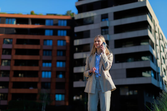 businesswoman stands outside in a city with modern buildings