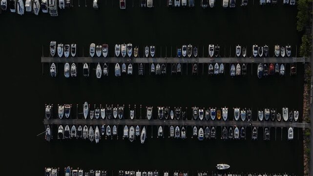 Drone footage captures organized marina with rows of docks and moored boats forming geometric symmetry along calm waterfront