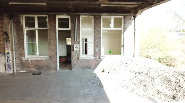 A sideways drone shot showing the former office buildings of an abandoned train station in Belgium. A busy station long time ago and now an urbex location