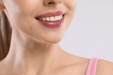 Obraz premium Happy woman with healthy teeth on light background, closeup