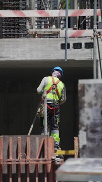Workers build a structure with safety measures in place at a construction site during the daytime
