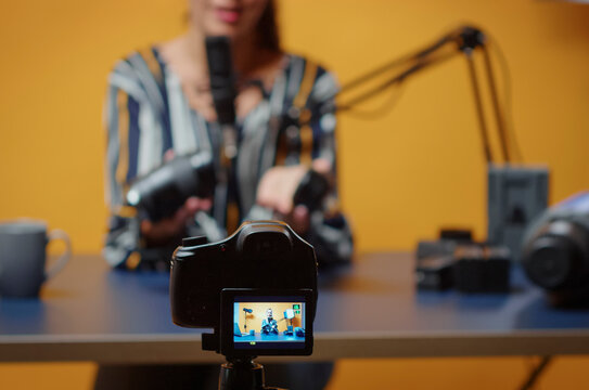 Content creator reviews camera lens in professional studio while explaining lighting equipment, modifier use and practical studio production for online video subscribers.