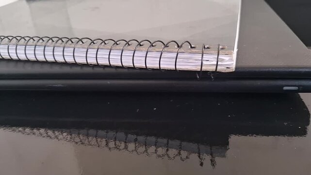 Spiral bound notebook resting on a black laptop motion footage