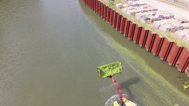 Aquatic Weed Harvester Clearing Green Vegetation From a Canal on a Sunny Summer Afternoon