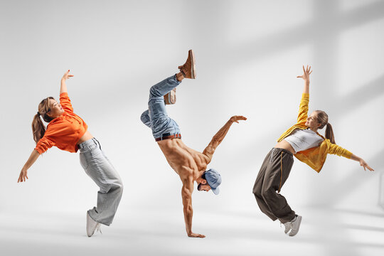Guy performing handstand and two girls dancing