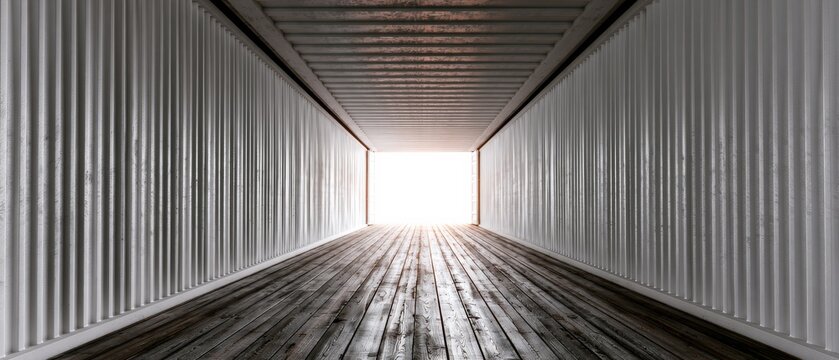 Light at the end of a shipping container tunnel shows wooden floor leading to the outside