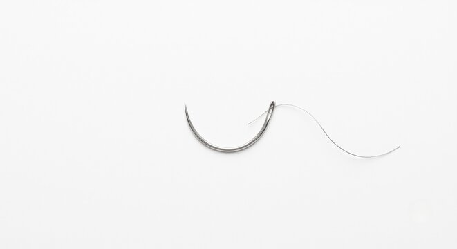 Sterile curved surgical needle on clinical white background