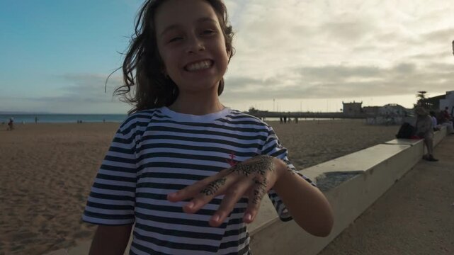 Young Girl with Henna Tattoo Smiles on Essaouira Beach, Morocco, Capturing Cultural Authenticity and Joy