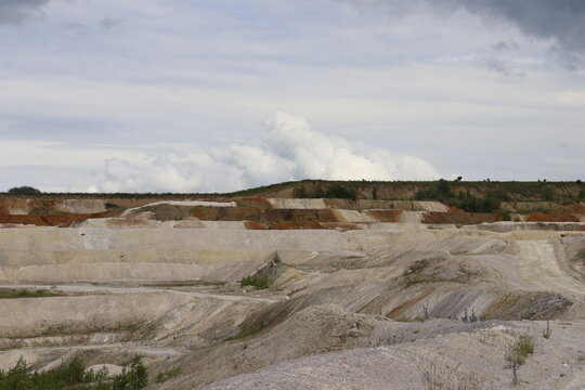 Layered kaolin quarry landscape with dramatic cloudy sky