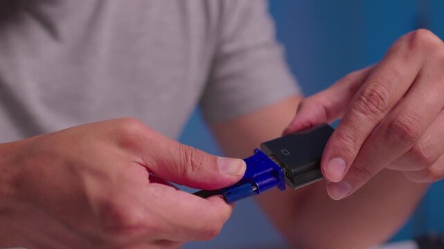 Hands guiding blue braided cable plug into black rectangular connector housing with steady forward pressure, precise alignment, and secure insertion during hands on assembly work