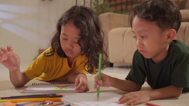 Brother and sister coloring with colored pencils in the living room, illustrating creative play, early childhood learning, family bonding, and home education.