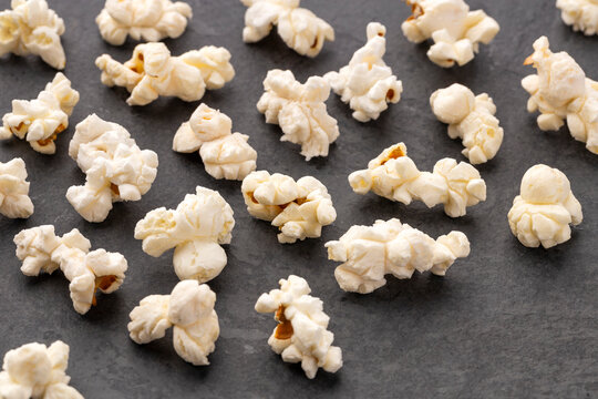 Above-ground view of natural popcorn on a black surface, ideal for movie, snack, and food concepts