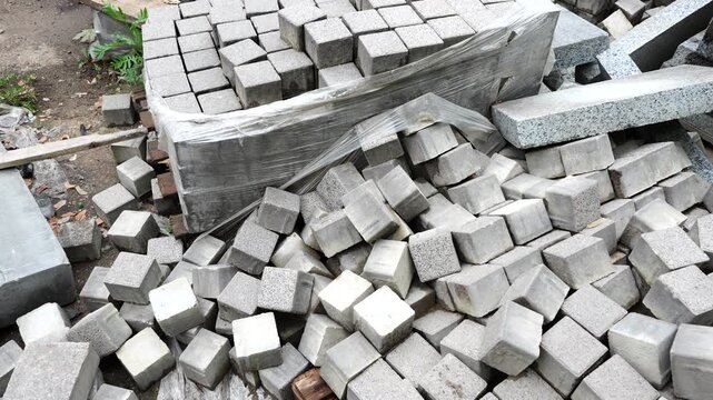 Stacked concrete paving blocks and construction materials prepared for sidewalk installation, urban improvement and infrastructure projects