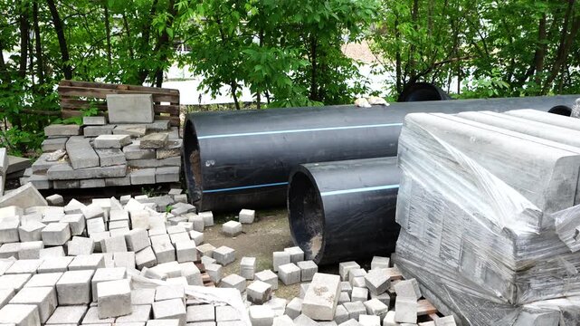 Large plastic utility pipes and paving materials prepared for infrastructure construction, urban improvement and engineering projects
