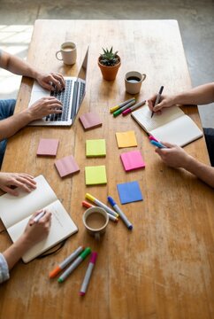 Overhead view of creative team brainstorming with colorful sticky notes and laptops