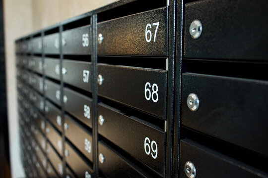metal mailboxes on a concrete building facade in a neutral side view of real estate commercial properties with black and gray tones and natural light, clean background.
