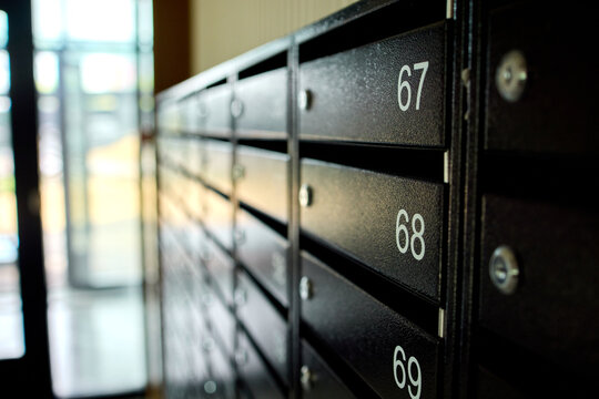 metal mailboxes on a concrete building facade in a neutral side view of real estate commercial properties with black and gray tones and natural light, clean background.