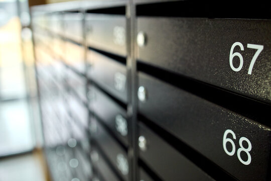 metal mailboxes on a concrete building facade in a neutral side view of real estate commercial properties with black and gray tones and natural light, clean background.
