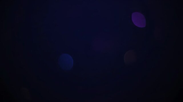 Abstract dark backdrop with out-of-focus circles of purple, blue, gold, and red