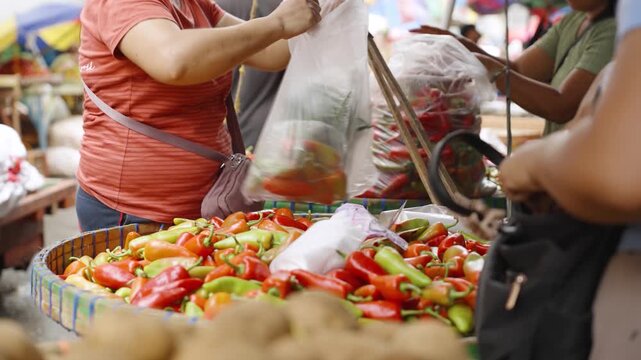 Customer Wrapping Fresh Chili Peppers While a Market Vendor Gives Change at a Street Market